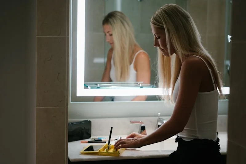 Person examining their complexion in bathroom mirror with natural lighting