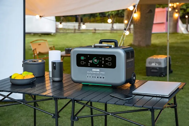 Portable power station being used to charge devices at an outdoor camping site with tent in background