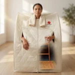 Person sitting inside a Therasage portable infrared sauna holding a glass of water
